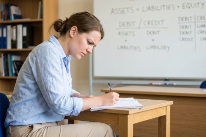 Jeune femme concentr&eacute;e prenant des notes en formation comptable